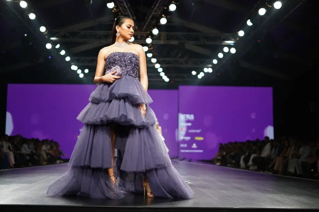 A picture of a fashion model showcasing a purple dress on a fashion week